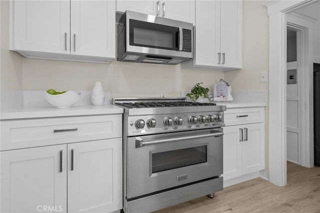 kitchen featuring light wood-type flooring, appliances with stainless steel finishes, light countertops, and white cabinets