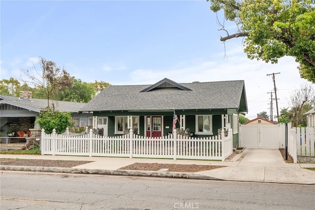 bungalow-style house with a fenced front yard, covered porch, driveway, roof with shingles, and a gate