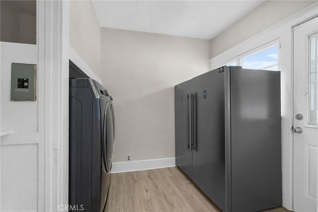 clothes washing area featuring laundry area, baseboards, light wood finished floors, and independent washer and dryer