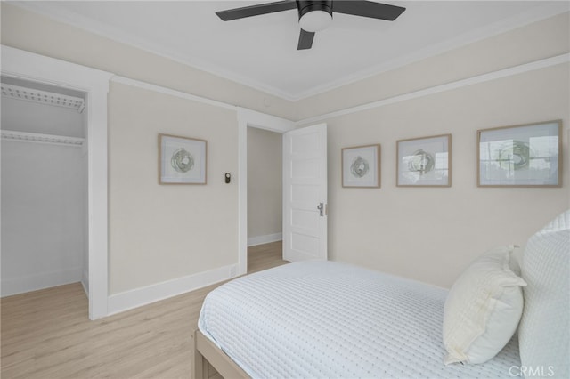 bedroom with ceiling fan, baseboards, a closet, light wood-type flooring, and crown molding