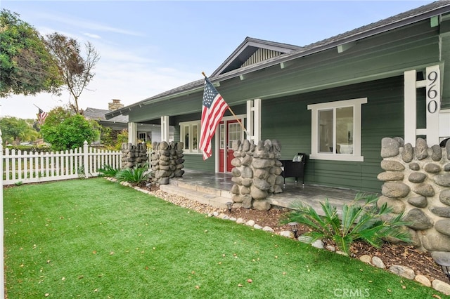 view of front of house with covered porch, a front lawn, and fence