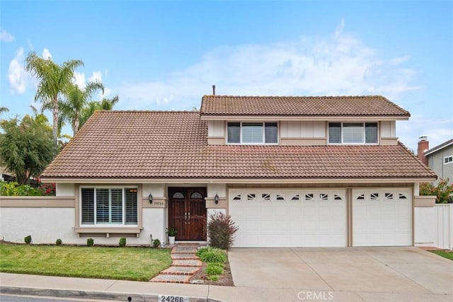 traditional-style house with concrete driveway, a tiled roof, fence, a front lawn, and stucco siding