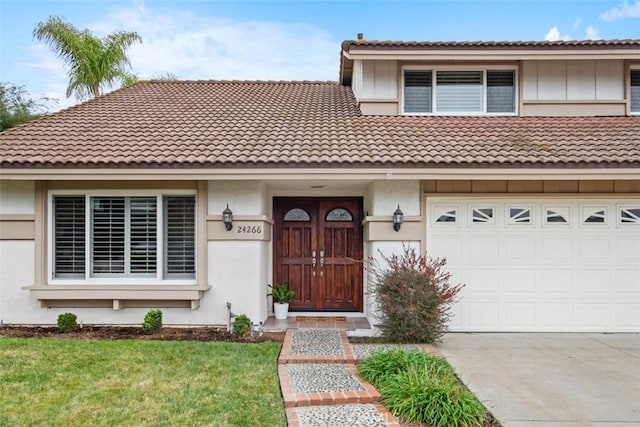 townhome / multi-family property with driveway, stucco siding, an attached garage, and a front yard