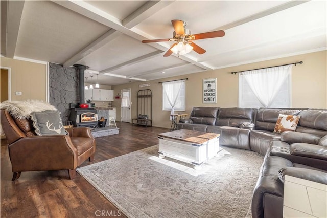 living area with dark wood-type flooring, beam ceiling, a wood stove, and a ceiling fan