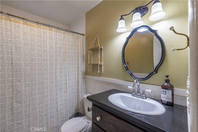 bathroom with toilet, curtained shower, vanity, and wainscoting