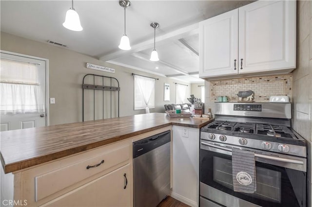 kitchen featuring butcher block counters, decorative backsplash, appliances with stainless steel finishes, white cabinetry, and a peninsula