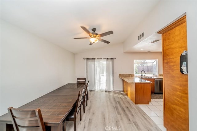 dining space with visible vents, ceiling fan, light wood-type flooring, and vaulted ceiling