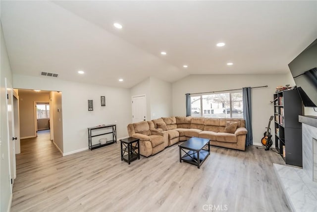 living room with recessed lighting, a fireplace, visible vents, vaulted ceiling, and light wood finished floors