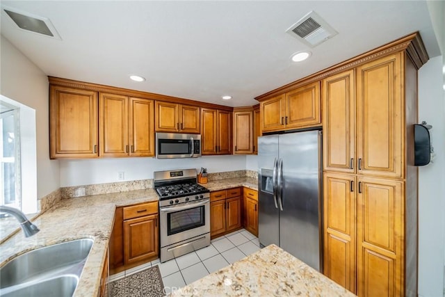 kitchen featuring visible vents, brown cabinets, stainless steel appliances, a sink, and light tile patterned flooring