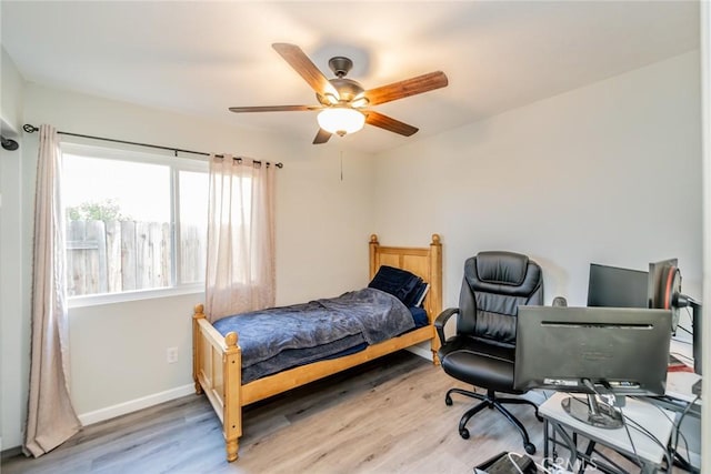 bedroom featuring wood finished floors, baseboards, and a ceiling fan
