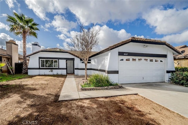 view of front facade with concrete driveway, a tile roof, a garage, and stucco siding