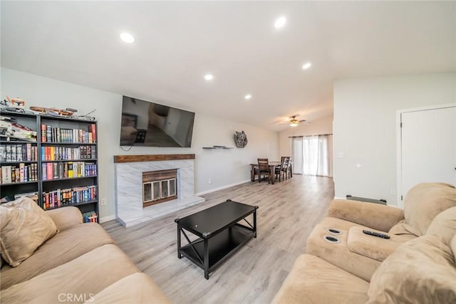 living area featuring a ceiling fan, recessed lighting, wood finished floors, a high end fireplace, and baseboards