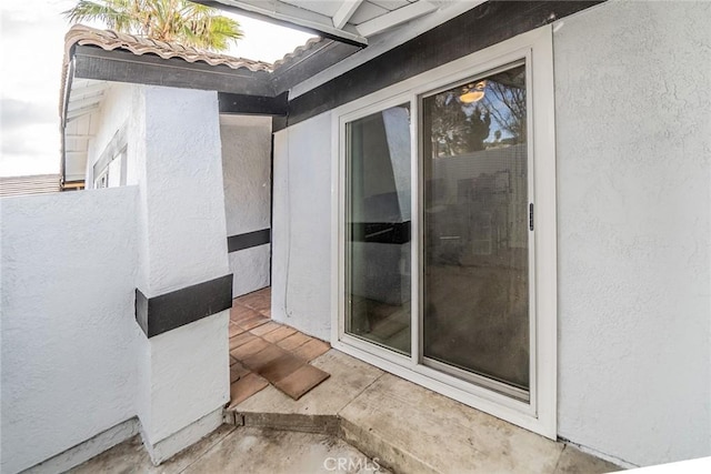 view of exterior entry featuring stucco siding and a tiled roof