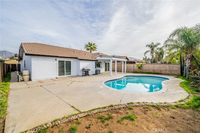 rear view of house with a patio area, a fenced backyard, a tiled roof, and stucco siding