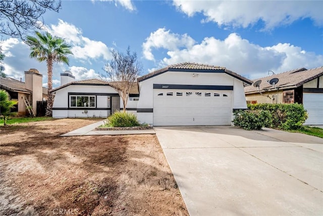 mediterranean / spanish house featuring an attached garage, concrete driveway, a tiled roof, stucco siding, and a chimney