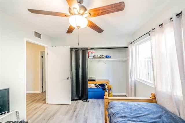 bedroom featuring baseboards, a closet, a ceiling fan, visible vents, and wood finished floors