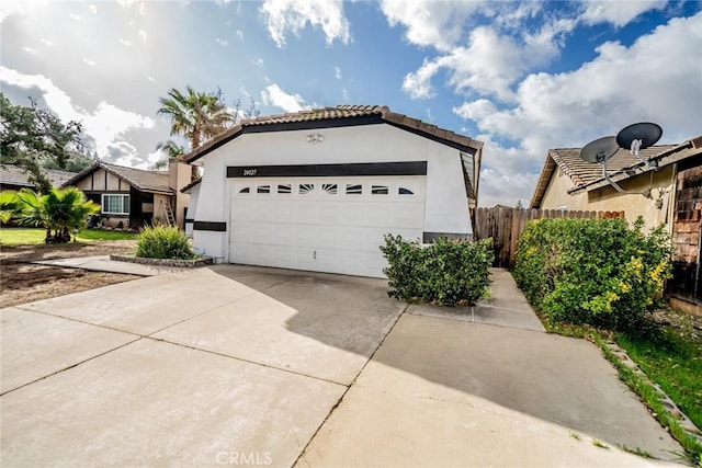 exterior space with driveway, an attached garage, fence, and stucco siding