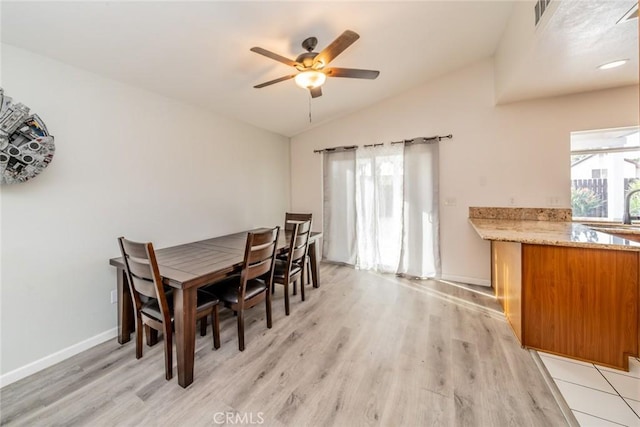 dining area with visible vents, baseboards, ceiling fan, light wood-style floors, and vaulted ceiling