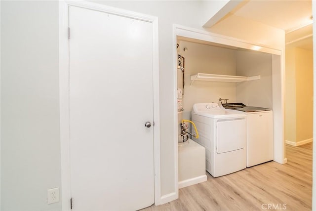 laundry room featuring light wood-type flooring, laundry area, baseboards, and washing machine and clothes dryer