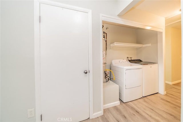 laundry room featuring washer and clothes dryer, light wood-style floors, laundry area, and baseboards