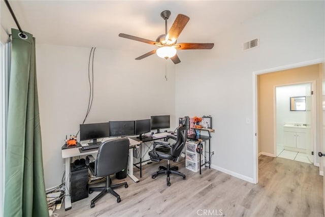 office space with a ceiling fan, visible vents, baseboards, and wood finished floors