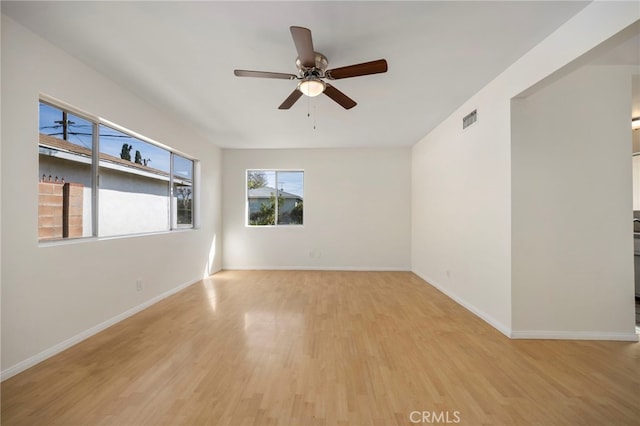 empty room featuring visible vents, ceiling fan, light wood-style flooring, and baseboards