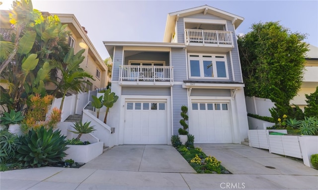 view of front of home with driveway, a balcony, an attached garage, and fence