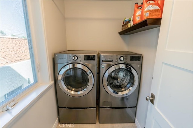 laundry area with baseboards, laundry area, washer and clothes dryer, and a healthy amount of sunlight