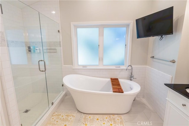 full bathroom with tile walls, a freestanding tub, vanity, and a shower stall