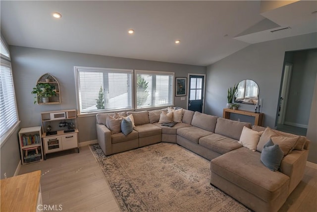 living area with lofted ceiling, light wood finished floors, baseboards, and visible vents