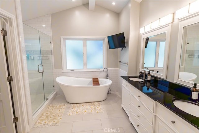 bathroom with tile walls, double vanity, a freestanding bath, a sink, and a shower stall