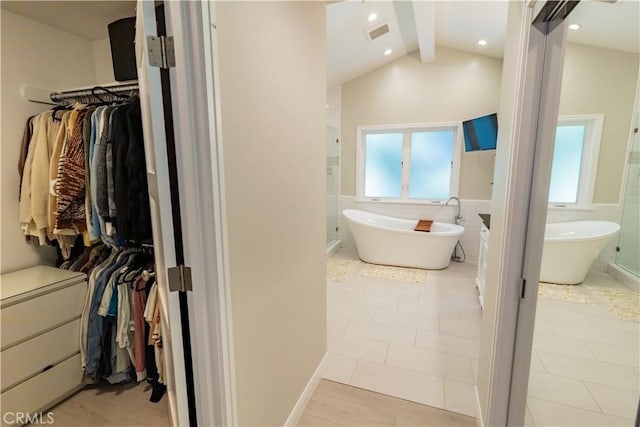 full bath with visible vents, a spacious closet, plenty of natural light, and tile walls