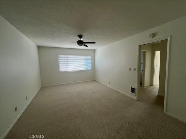 unfurnished room with carpet floors, visible vents, a textured ceiling, and baseboards