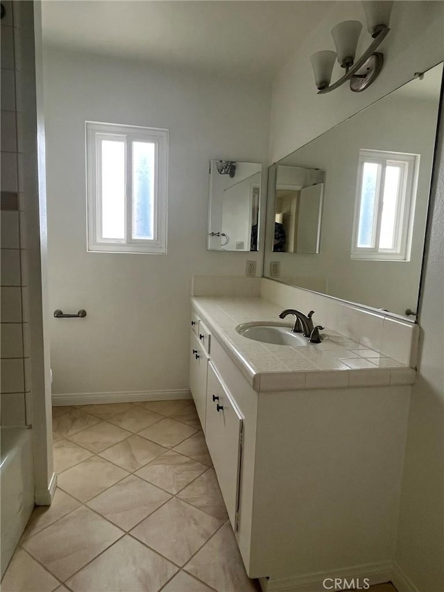 full bath featuring a healthy amount of sunlight, vanity, baseboards, and tile patterned floors