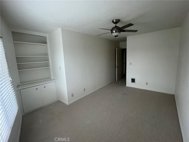 empty room with light carpet, visible vents, a ceiling fan, and a textured ceiling