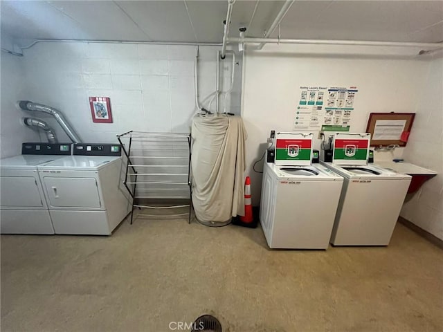 common laundry area with concrete block wall and washer and clothes dryer