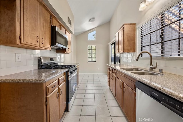 kitchen featuring light tile patterned floors, visible vents, vaulted ceiling, stainless steel appliances, and a sink