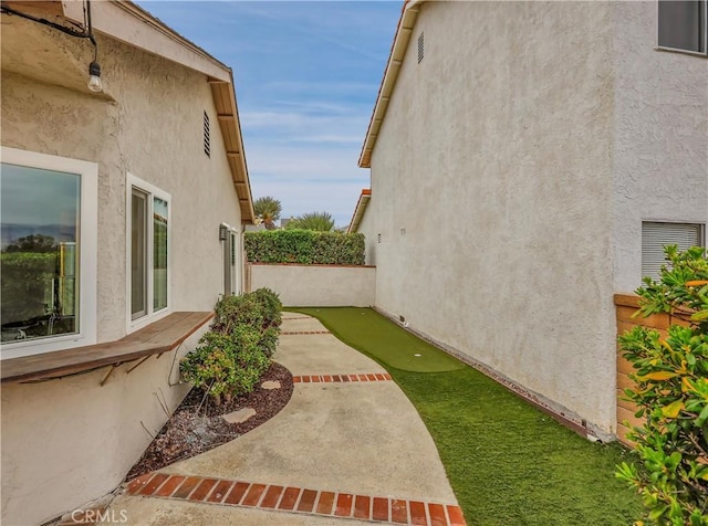 view of home's exterior with stucco siding, fence, and a patio