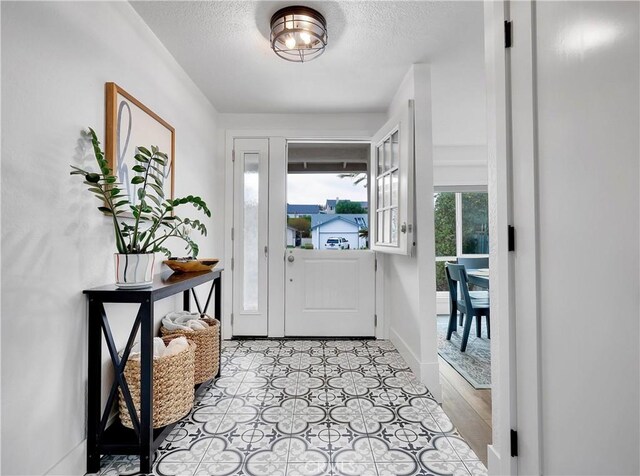 foyer with a textured ceiling and baseboards