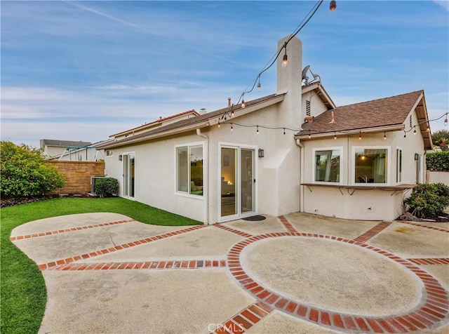 back of property featuring a chimney, a patio area, fence, and stucco siding