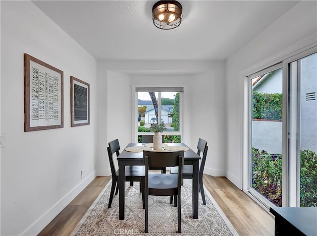 dining space with baseboards and wood finished floors