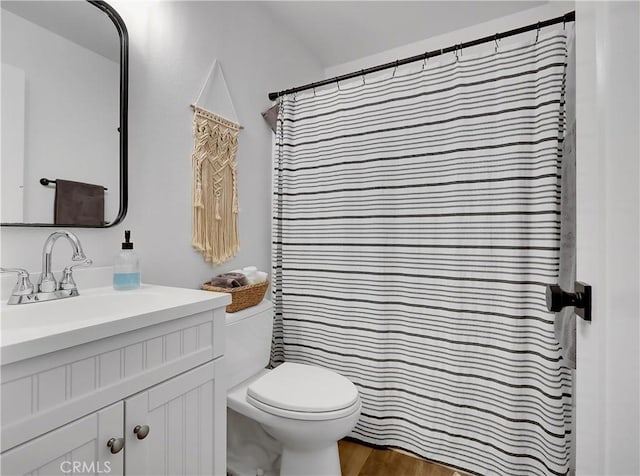 bathroom with toilet, wood finished floors, and vanity