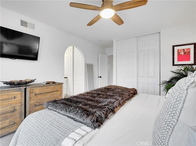 bedroom with ceiling fan, visible vents, and arched walkways