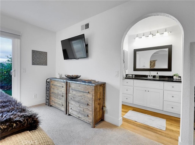 bedroom featuring baseboards, visible vents, a sink, and light colored carpet