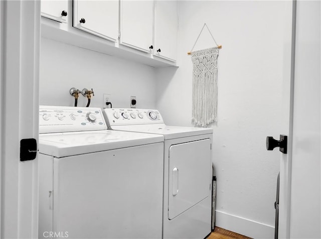 clothes washing area with washer and dryer, cabinet space, and baseboards