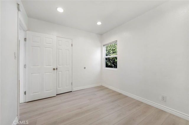 unfurnished bedroom with light wood-type flooring, baseboards, a closet, and recessed lighting