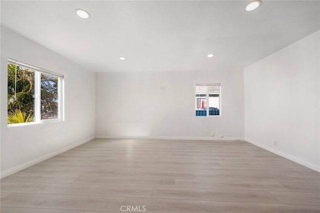 spare room with baseboards, light wood-style flooring, and recessed lighting