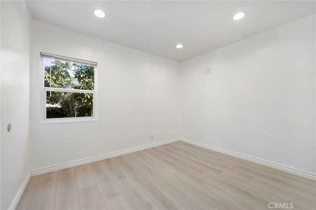 spare room featuring light wood-type flooring, baseboards, and recessed lighting