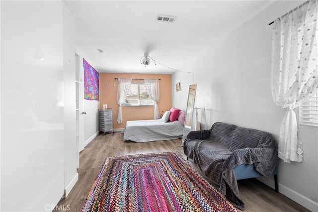 bedroom with visible vents, baseboards, and wood finished floors