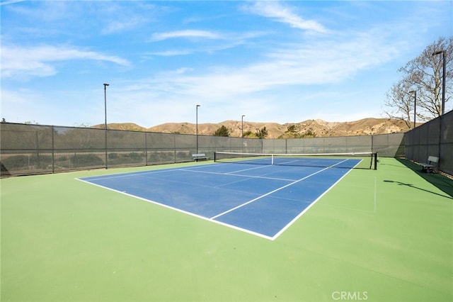 view of tennis court with fence and a mountain view